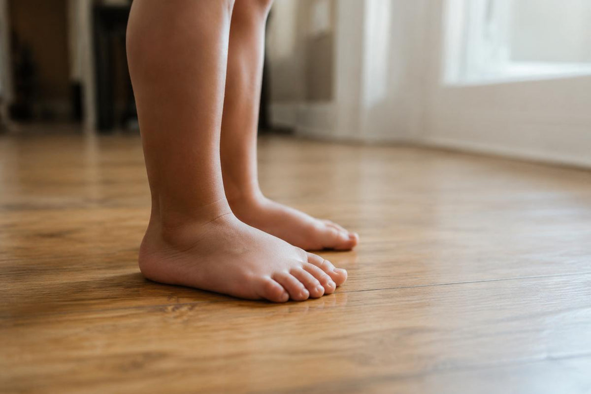 A toddler standing barefoot on a wooden floor